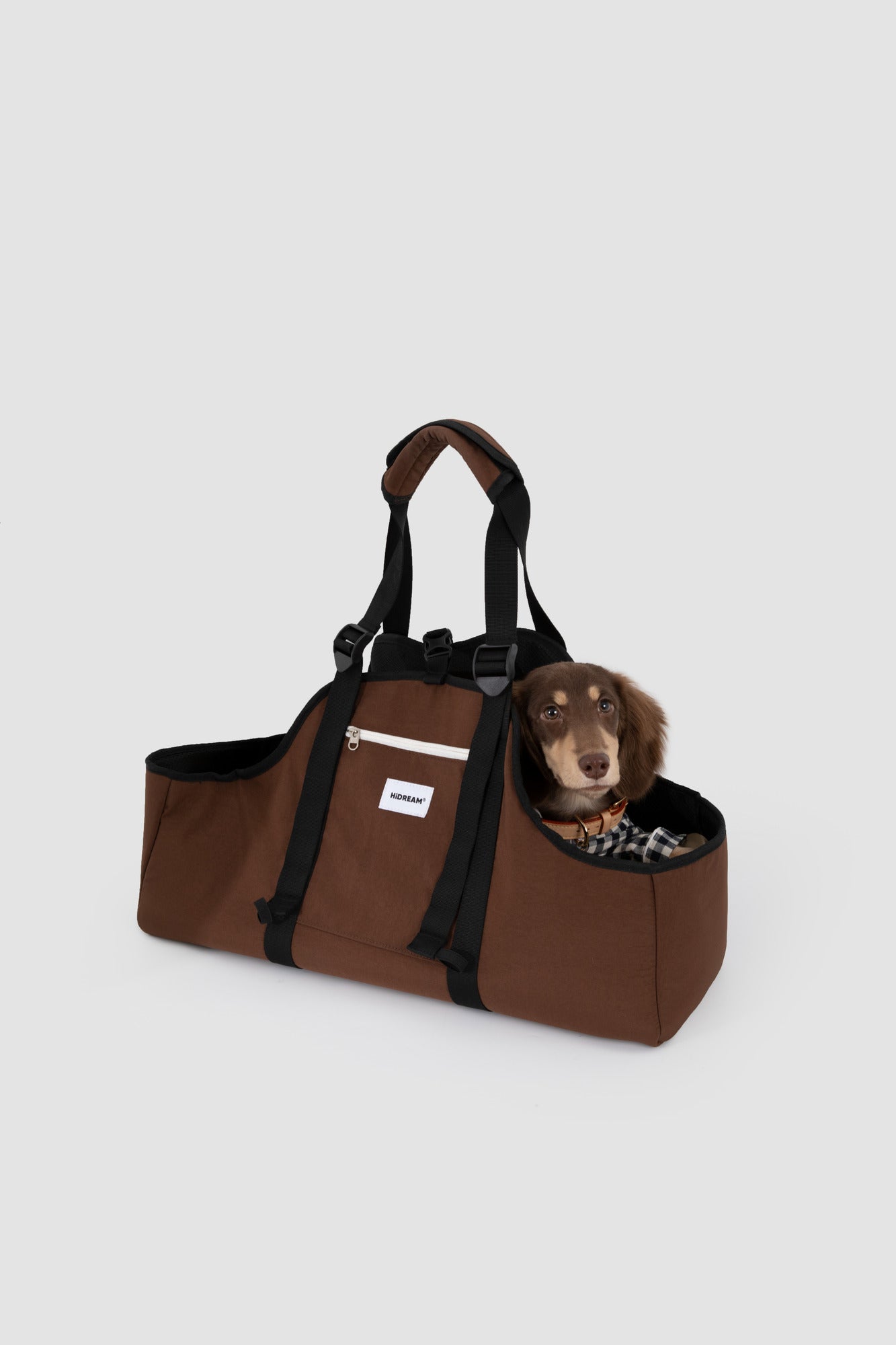 Angled view of a dachshund resting in the brown carrier, showing its low open sides.
