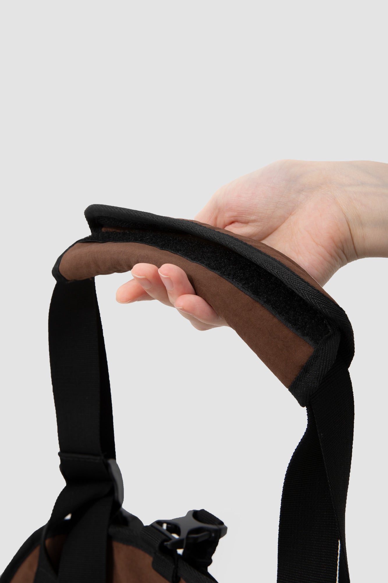 Close-up of the padded brown shoulder wrap and adjustable black webbing.